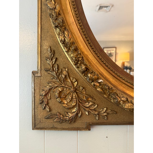 This mirror is within a square frame and oval cutout with foliate trim in a satin and burnished finish. At each corner are...