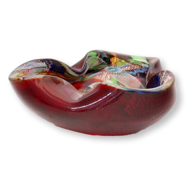 Striking Mid-20th Century Murano art glass bowl in a rich ruby red hue with an undulating freeform rim. The interior...