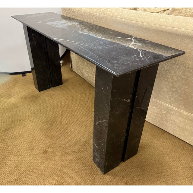 Striking post modern black marble console table is crafted from richly veined black marble and boasts a sleek rectangular...