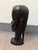 A beautifully carved ebony wood bust featuring refined facial contours, smooth polished surfaces, and a textured hair...