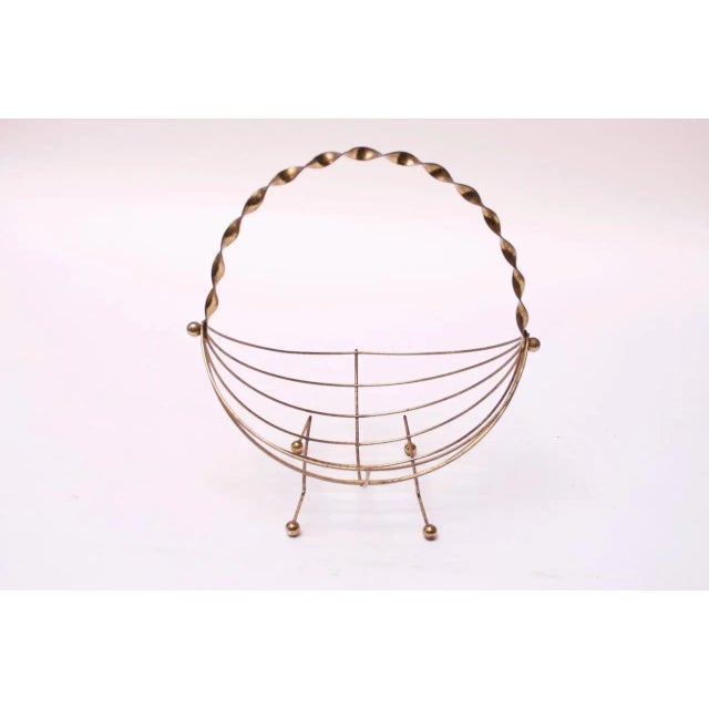 Shapely circa 1950s American basket composed of wire brass rods, a braided handle and ball feet. Suitable for holding...