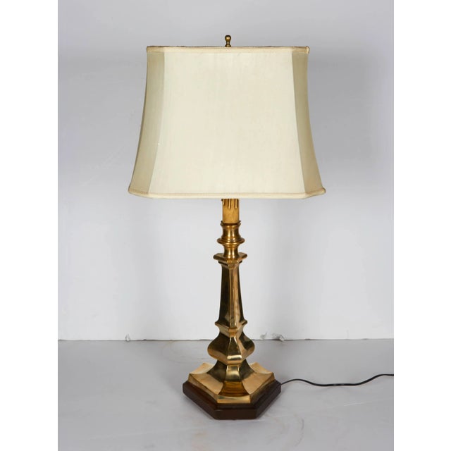 Italian classical style candlestick table lamp. Cast in solid brass in a triangular design and resting on a wood base....