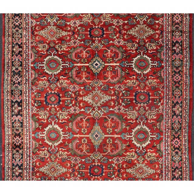 This rug is replete with an all-over symmetrical sub-geometric design set upon a red background and enclosed within a...