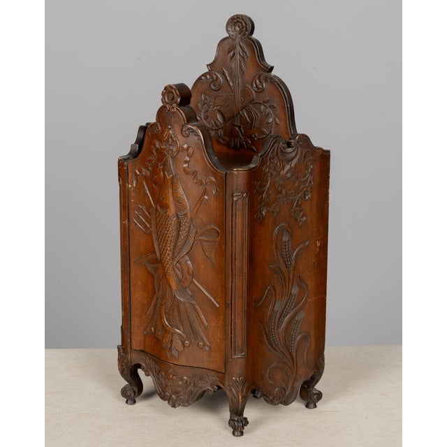A 19th century French fariniere made of walnut with nicely detailed hand-carved decorative motifs: fishes on front panel,...