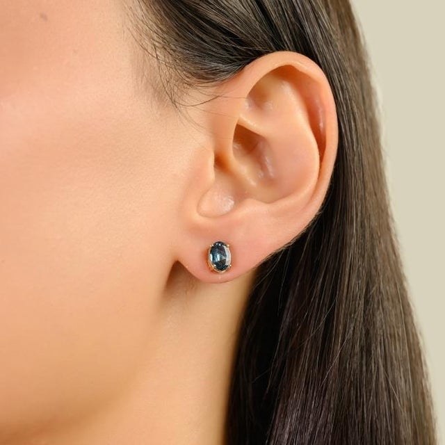 Elegant stud earrings featuring two oval-cut blue sapphires totaling 1.88 carats, beautifully set in 14K solid yellow...