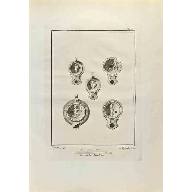 Oil Lamps with Hermes God from "Antiquities of Herculaneum" is an etching on paper realized by C. Pignatari in the 18th...