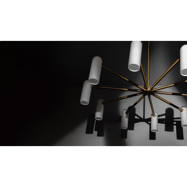 Spokes of brass hold slender lampshades, the circle of light creating a planetary effect in this striking round...