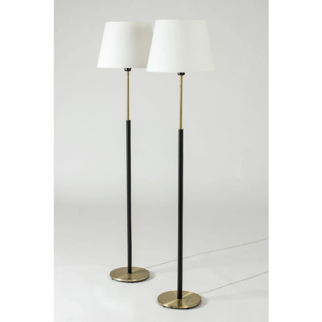 This is a pair of elegant floor lamps from Falkenbergs Belysning, made from brass. The sleek stems are dressed with black...