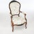 An antique pair of Victorian parlor armchairs offer rosewood construction with carved floral crest over upholstered seat,...