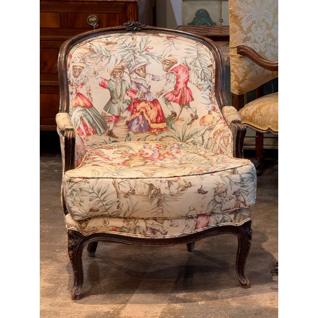 Vintage French bergère with an arched back and carved floral crest, on cabriole legs with carved knees. The dark finish...