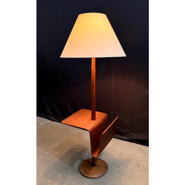 This walnut floor lamp by Laurel Lamp Company combines three functions in one elegant form: a turned round base supports a...