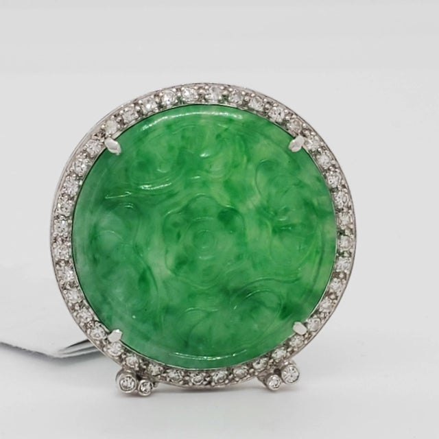 Gorgeous big carved green jade round with 0.10 ct. good quality white diamond rounds. Handmade in platinum. Metal:...