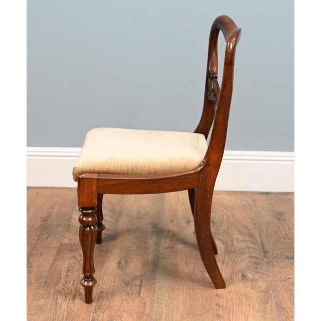 A handsome set of six Victorian mahogany dining chairs with elegant balloon backs Each shaped back has a carved cross rail...