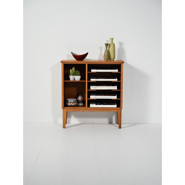 Scandinavian open oak cabinet with shaped magazine/record shelves, two side compartments, and slanted legs. Clean lines...