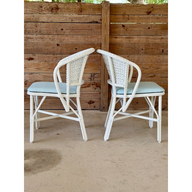A charming pair of vintage Whitecraft rattan dining chairs featuring woven lattice backs, curved arms, and a timeless...