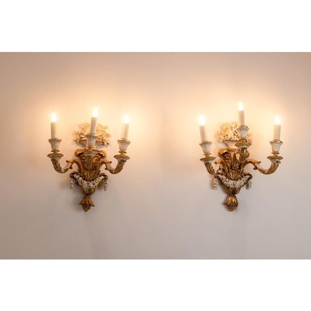 Pair of Louis XVI style wall lights in carved, gilded and lacquered wood, with three arms of light, decorated with a...