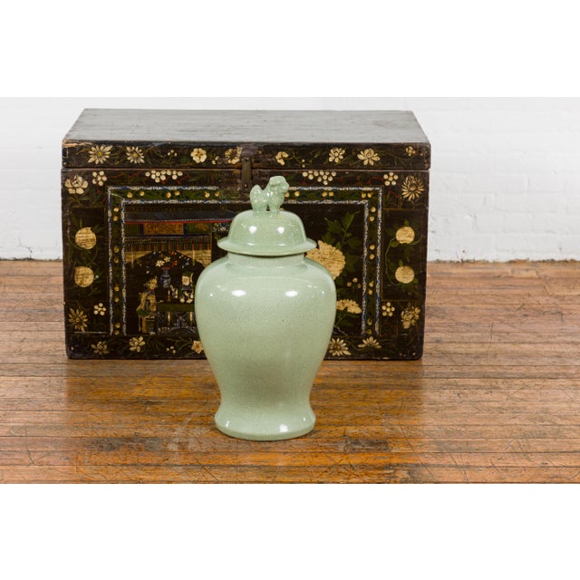 A vintage Chinese crackle green celadon lidded vase from the mid 20th century with stylized foo dog finial and tapering...