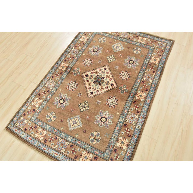 A tribal Caucasian Kazak rug hand-knotted with an all-wool pile on a cotton foundation. This oriental rug features a...