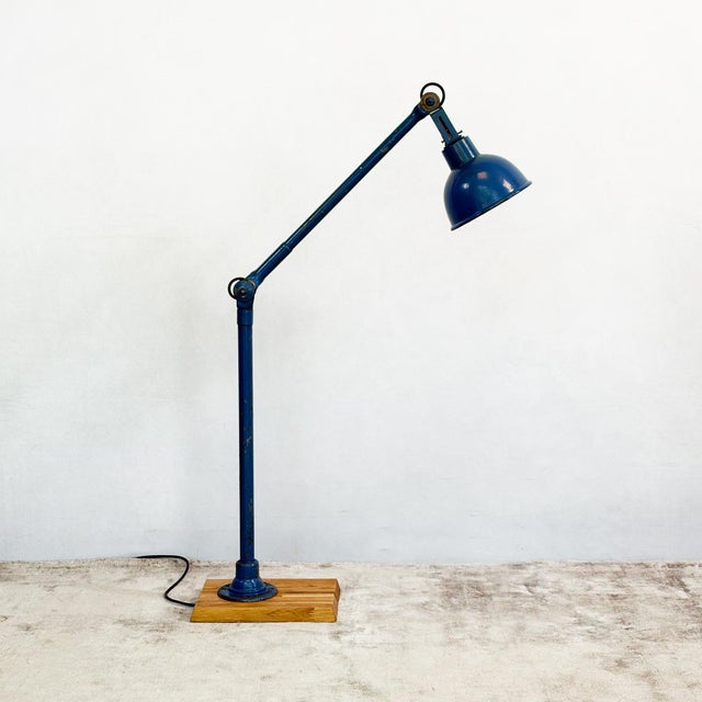 An articulated industrial lamp by dugdills, built from tubular steel and mounted on a wooden block base. The upright rises...