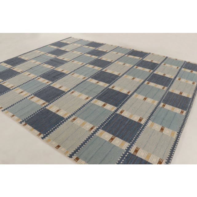 This oversized 11x13 Scandinavian rug showcases a geometric plaid-inspired design in powder blue, denim, ivory, beige, and...