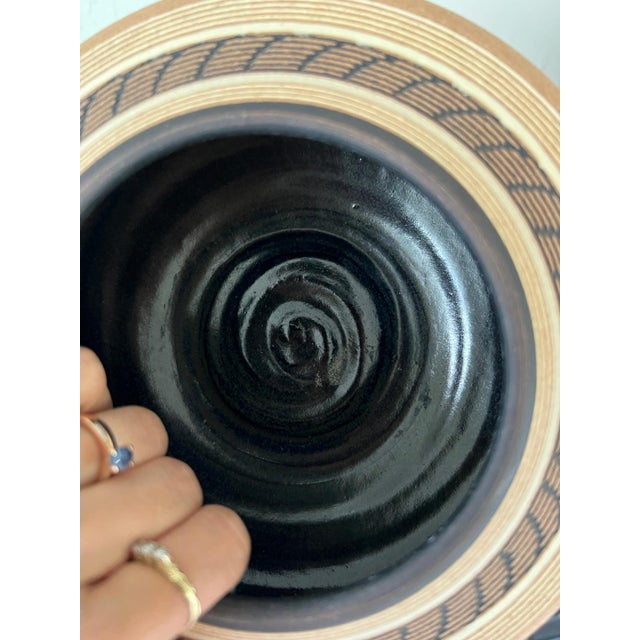 Signed Renee Margolin studio pottery low bowl with sgraffito banding, c.1980s-90s. Black interior, tan body with incised...