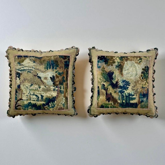 This matching pair of 18th-century antique tapestry pillows features a sophisticated floral design rendered in a muted...