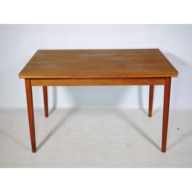 Extendable Danish design dining table in teak from the 1960s. Simple, clean design with slender, tapered legs and a...