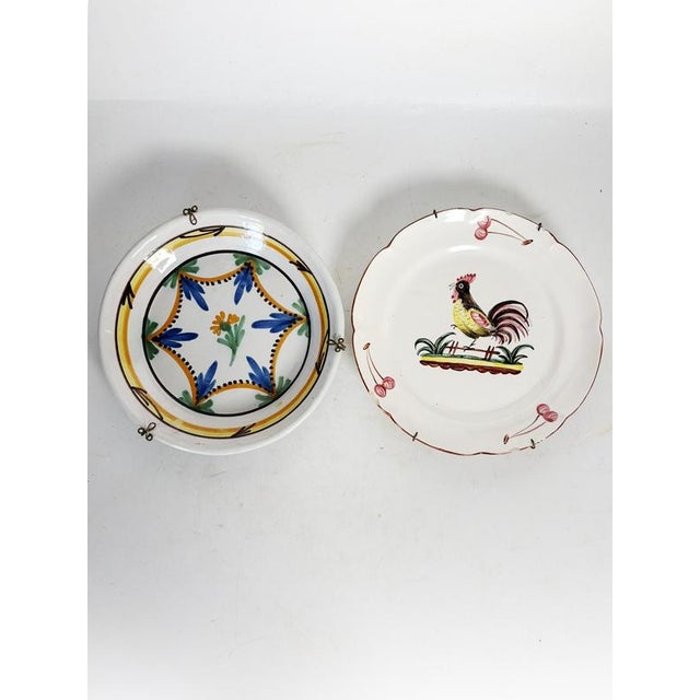 A set of two antique ceramic plates, France, 19th century, hand-decorated with traditional motifs. Each piece features a...