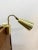 A german reading lamp with adjustable bracket in a brass-colored aluminum conical shaped lampshade, perforated with small...