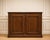 A low Regency-style sideboard with two doors, crafted from solid oak with a dark brown stain, resting on a wide, molded...