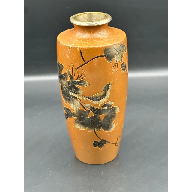 A beautifully hand painted Japanese ceramic vase featuring a warm persimmon toned ground with black and gold enamel...