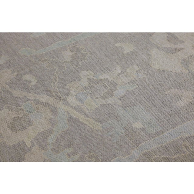 This modern Turkish Oushak rug is a stunning piece of art that has been handwoven using traditional techniques by skilled...