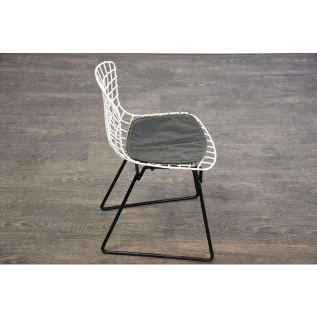 A mid century modern white and black wire child’s chair designed by Harry Bertoia for Knoll bearing the original knoll...