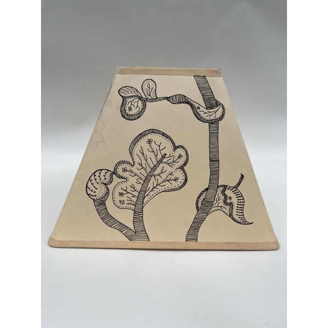 A single square shaped tapered tan colored paper lamp shade featuring hand drawn “Tree of Life” pattern inspired by...