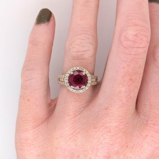 A ruby sits in a vivid red at the centre of this solid 14K yellow gold ring, encircled by sixty earth-mined diamonds. Ruby...