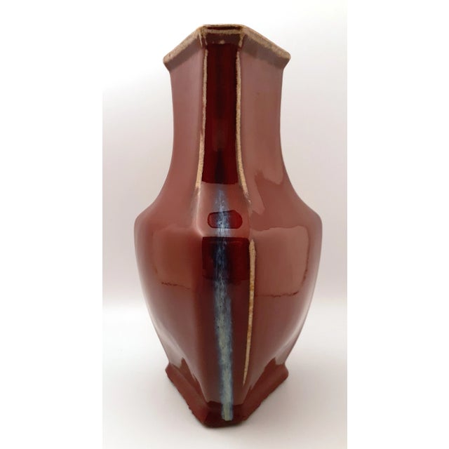 Chinese porcelain flambe glazed triangular vase, deep oxblood glaze laced with ecru and bluish-white striations on the...