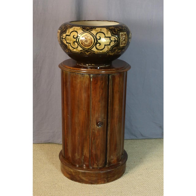 A mahogany side table that doubles as a daybed and opens with a door. The interior has a shelf. This side table is in its...