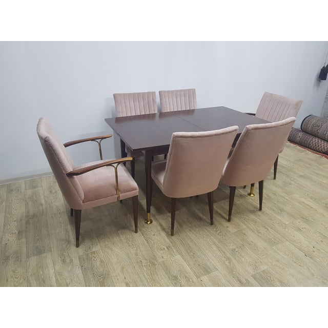Elegant table set with six chairs, two of which have armrests and brass bases. The set was made in the 1960s/70s. It has...