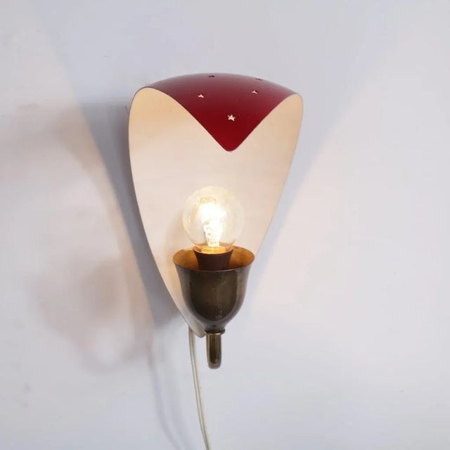 A lovely wall lamp made of high-quality red lacquered metal with perforated star-shaped details. This piece excels in...