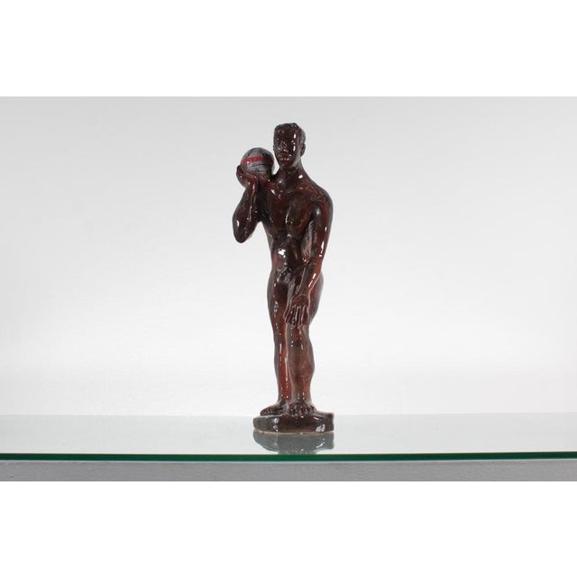 Glossy enamel porcelain sculpture, depicting Atlas holding the world. On the base, engraved, undeciphered signature....