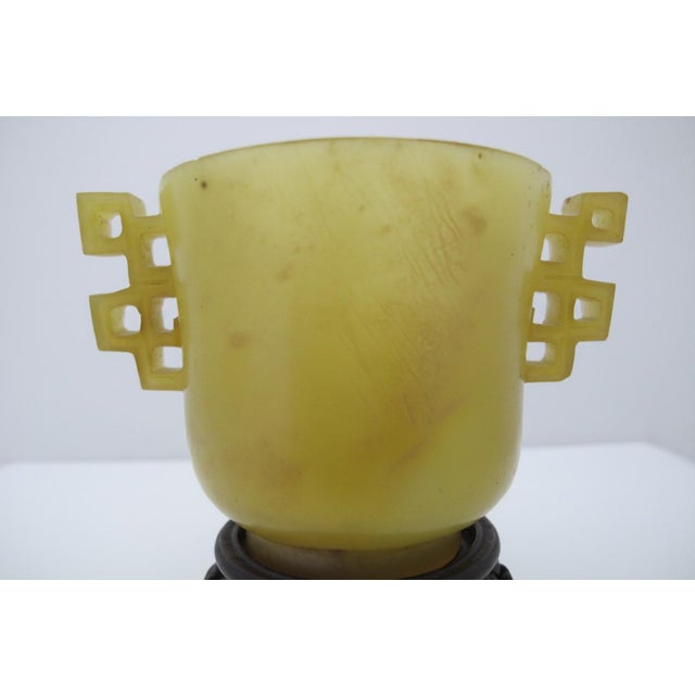 Chinese jade archaistic libation cup from the Qing dynasty, featuring geometric double handle designs. Carved from...