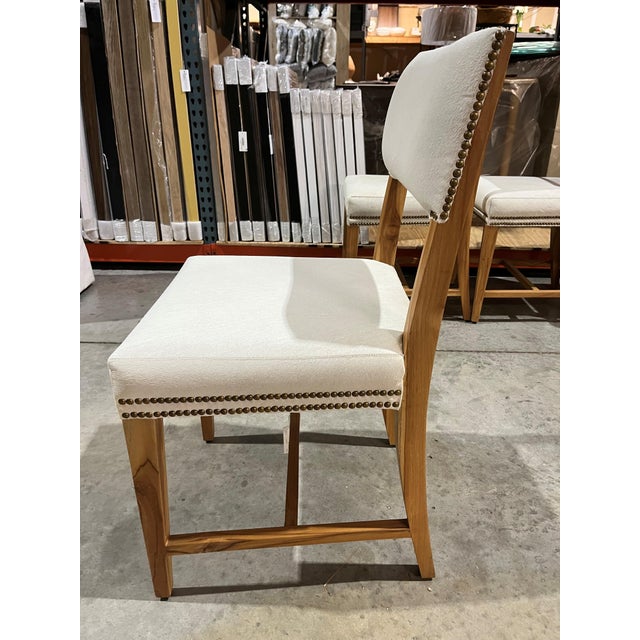This refined side chair features ivory hide, warm teak tapered legs and distinctive double rows of bronze nail heads for a...