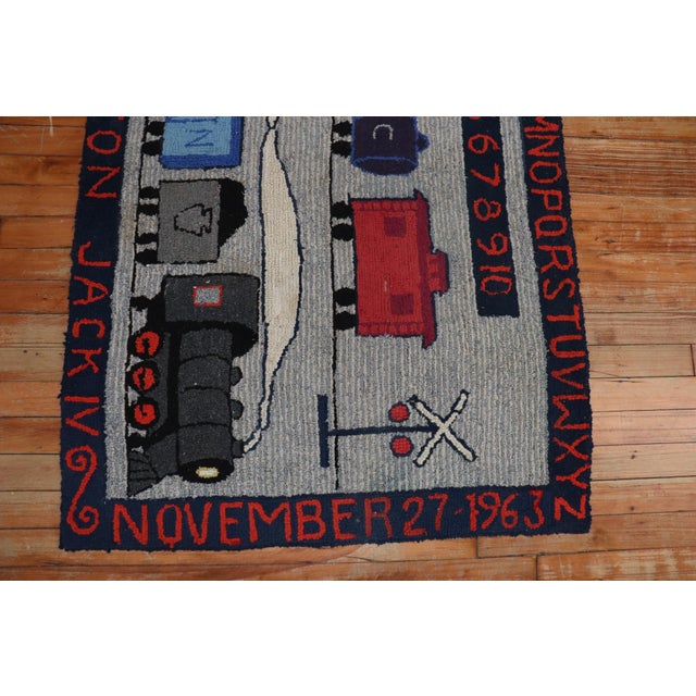 A 20th century pictorial rug with trains on a gray ground. The border has the exact date the rug was completed, the area,...