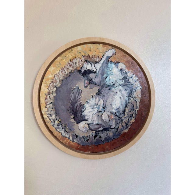 This circular oil painting on birch panel captures a serene moment of a cat curled up in a cozy nest. The soft, textured...