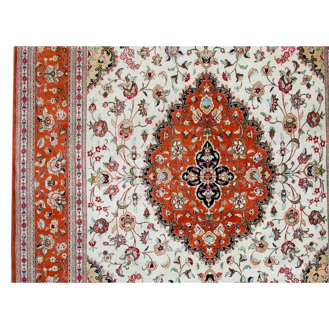 A stunning late 20th century Persian Qum 100% silk rug with a large central floral medallion floating amidst a field of...