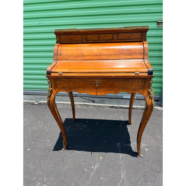 Beautiful French Louis XV style roll-top writing desk featuring rich burl wood veneers, brass gallery, ornate ormolu...