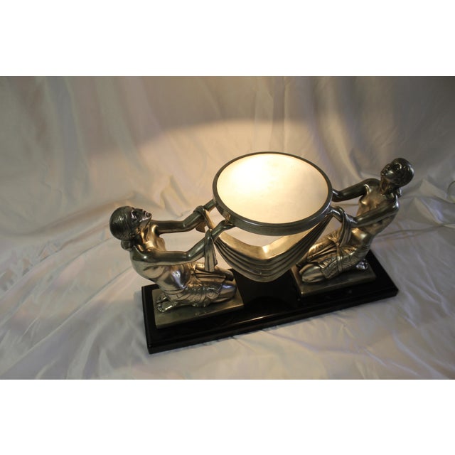 An Art Deco lamp with two girls holding an Alabaster shade. Mounted on an absolute black marble base . Good size and looks...