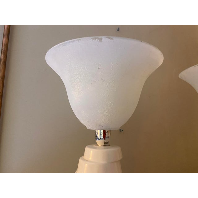 and elegant flared frosted glass shades. The distinctive asymmetrical bases feature sweeping, tiered ridges that create a...
