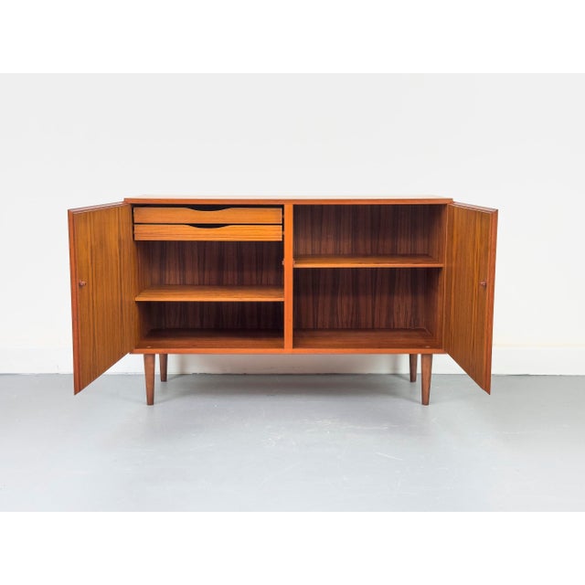 Teak sideboard with two handleless cabinet doors featuring solid wood edges. Beautiful grain and high-quality...