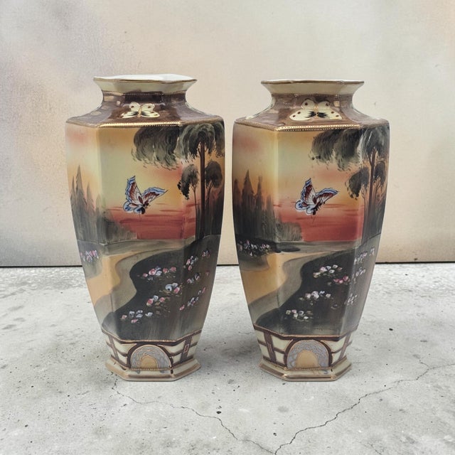 A refined pair of antique Nippon porcelain vases, produced for export during the early 20th century. Each faceted form is...